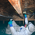 Technicians performing mold remediation in a crawl space beneath a home